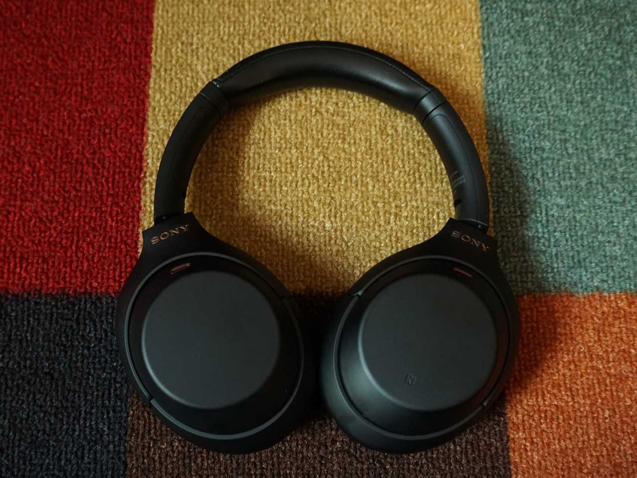 The Sony WH-1000XM4 sitting on a patterned carpet - best noise-cancelling over-ear headphones