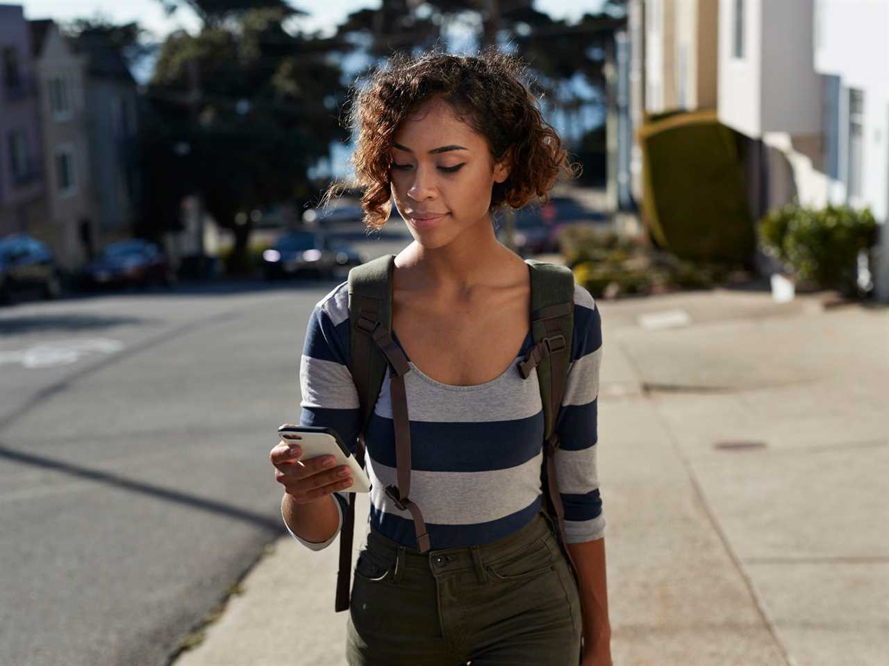 A young Gen Z person walking and looking at phone