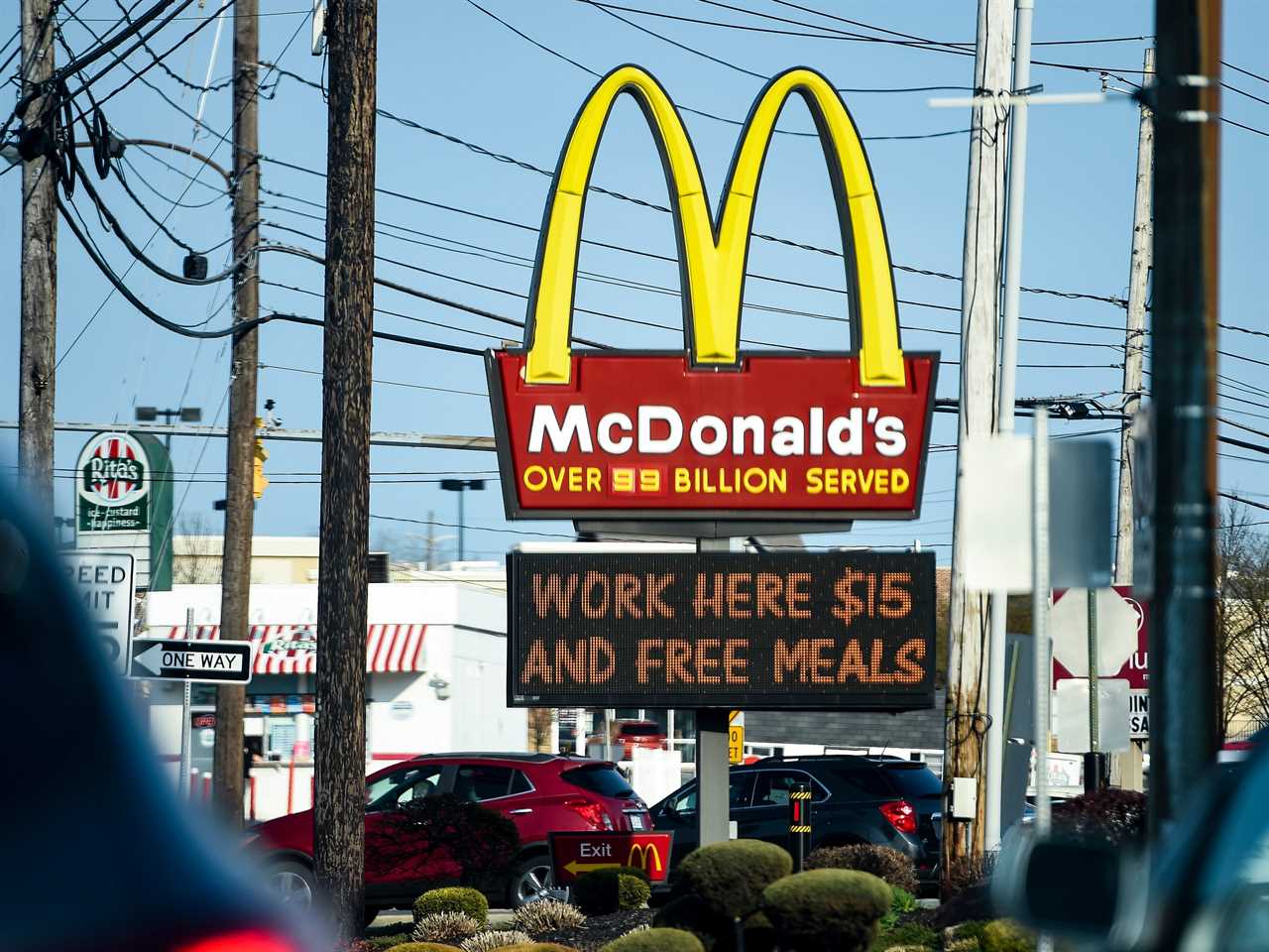 A McDonald's logo with a billboard below that says "work here $15 and free meals"