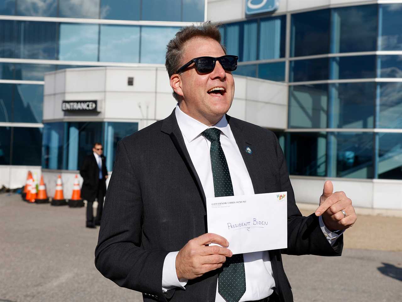 New Hampshire Republican Gov. Chris Sununu speaks to the media about a hand written birthday card for President Joe Biden as he awaited Biden's arrival on Air Force One Tuesday, Nov. 16, 2021, in Manchester, N.H.